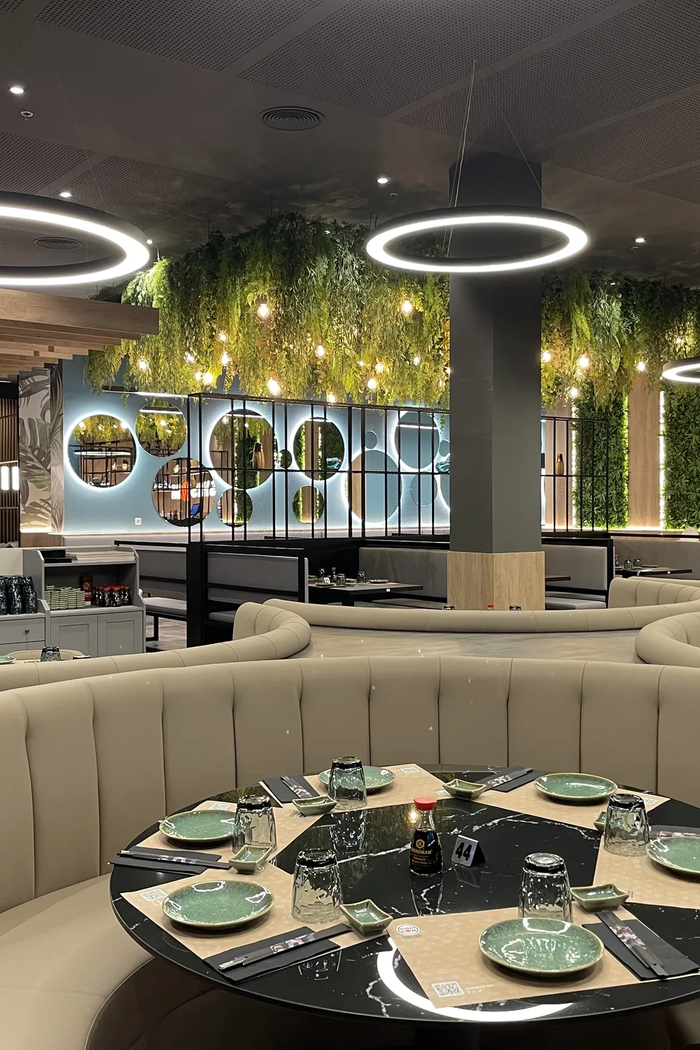 Reservado curvo con mesa redonda bajo aros de luz — Sushisom Viladecans Style Outlet